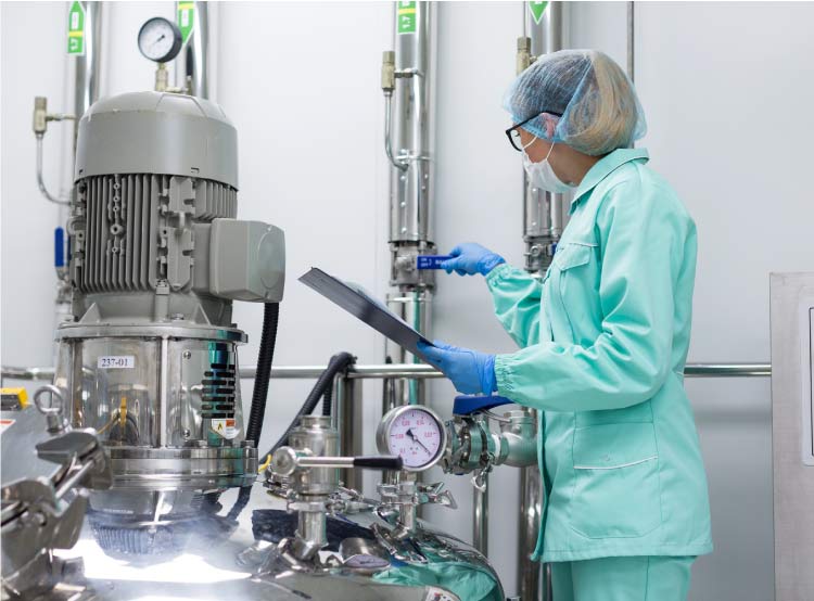 food-control Food safety consultant reviewing valve and gauge on a high-hygiene stainless steel reactor for infant formula production.