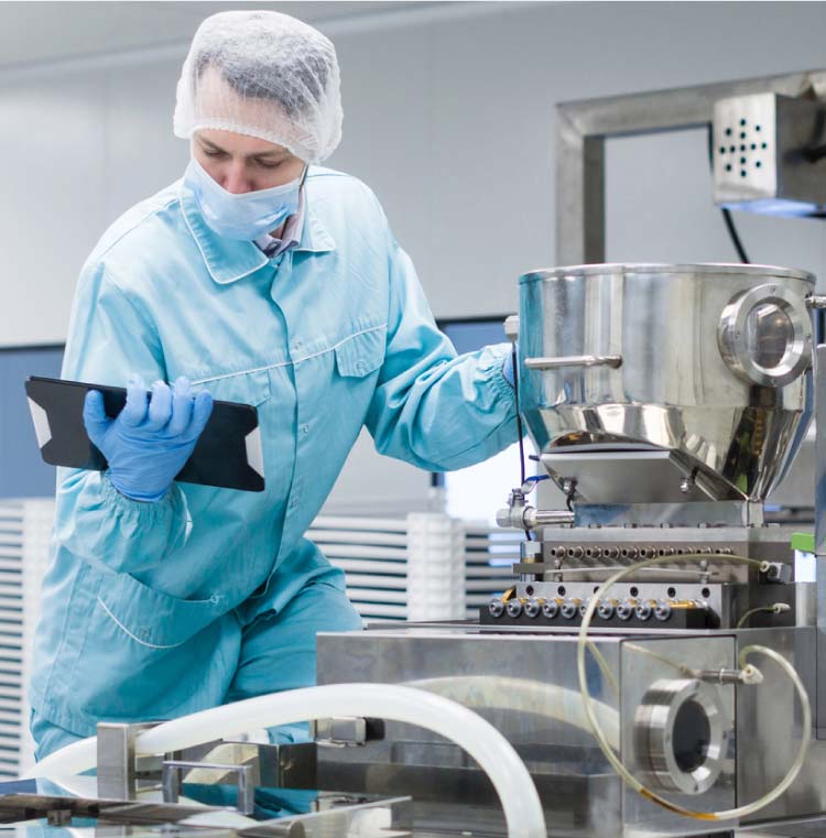 gfsi-control Food safety auditor wearing full blue personal protective equipment (PPE) and a hairnet using a digital tablet to conduct a rigorous GFSI compliance inspection on stainless steel processing machinery