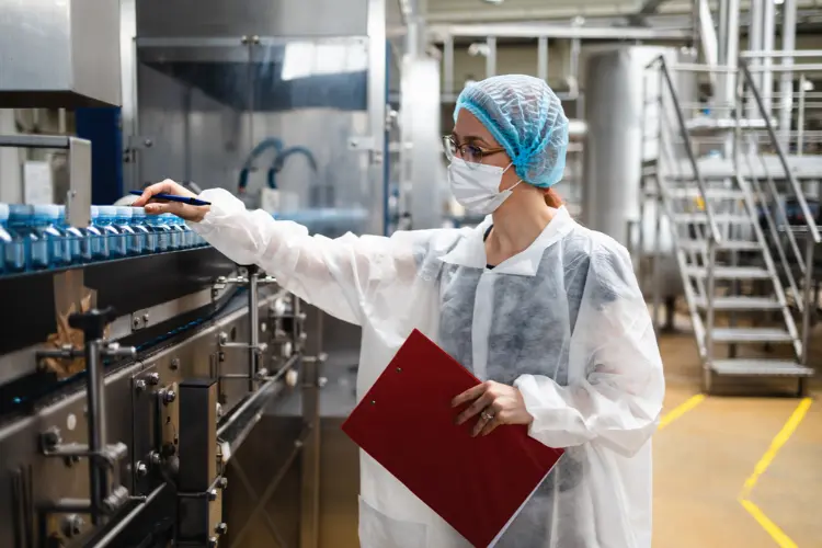 Food safety auditor inspecting bottled products on a production line during a GMP audit
